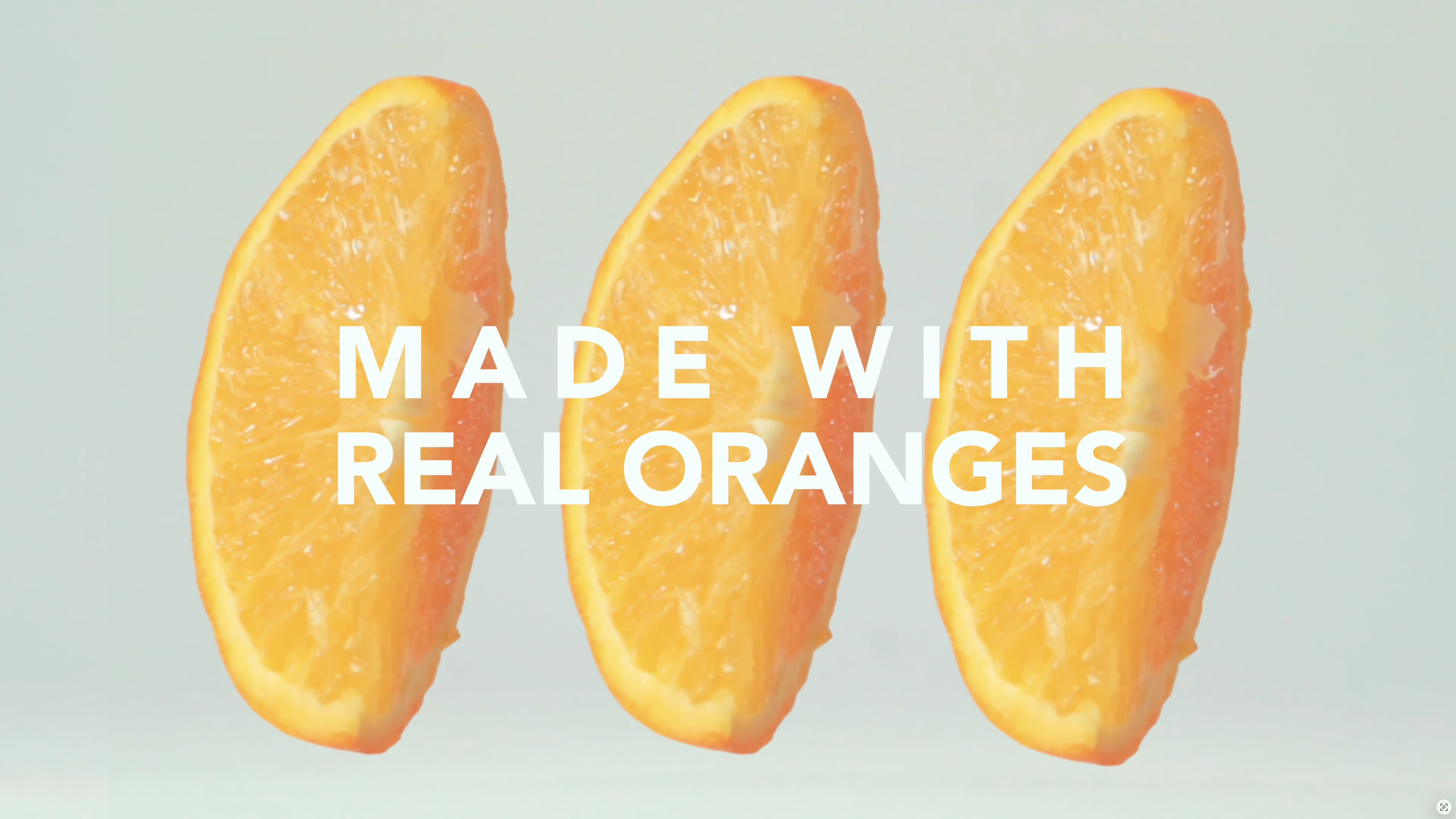 Three orange slices arranged in a row against a light gray background with the white text MADE WITH REAL ORANGES overlaid in the center.
